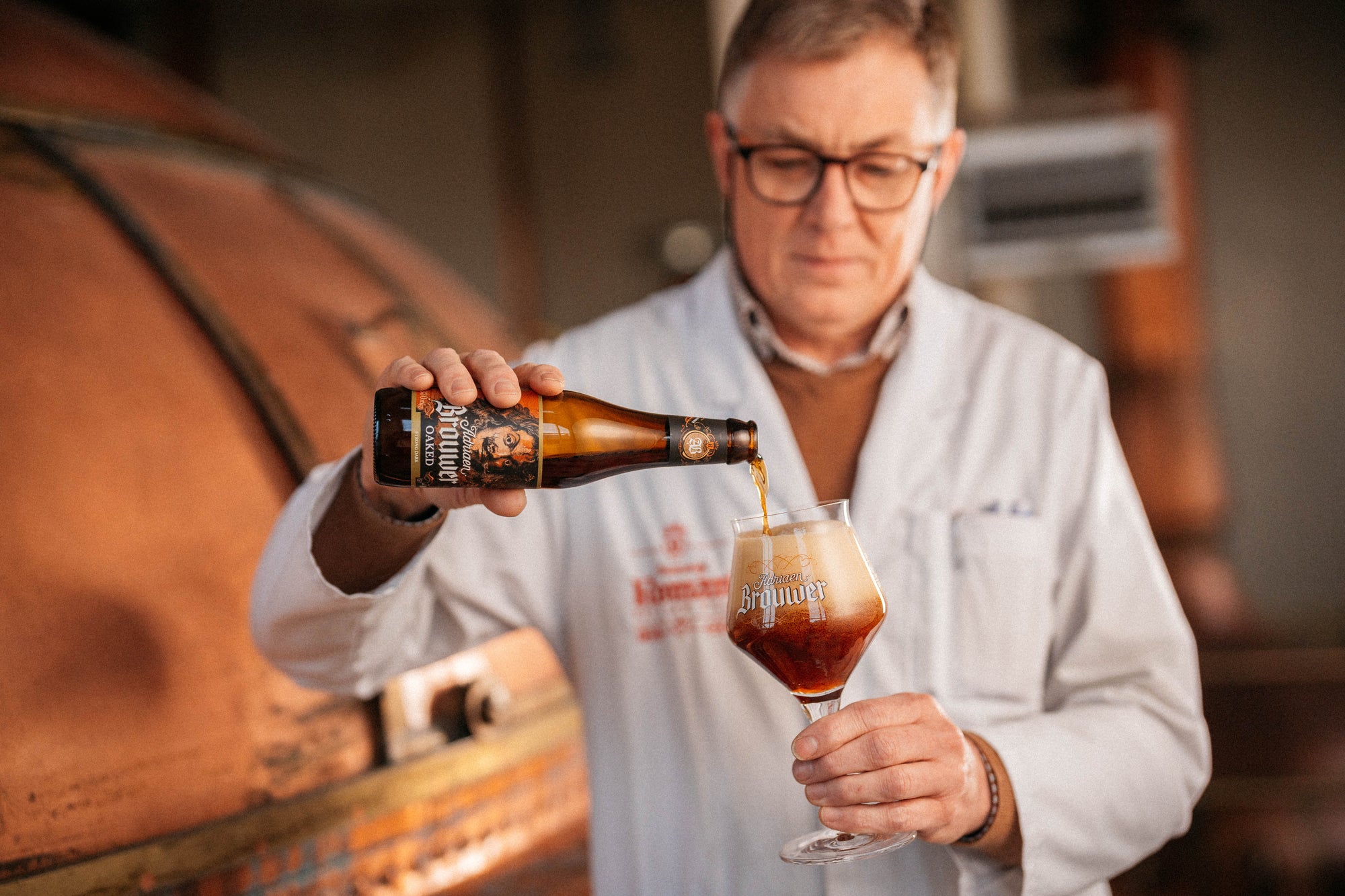 Brouwer giet een fles Adriaen Brouwer Oaked donkerbruin bier uit in een glas